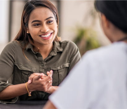 An adult clasps their hands together while happily talking to their provider.